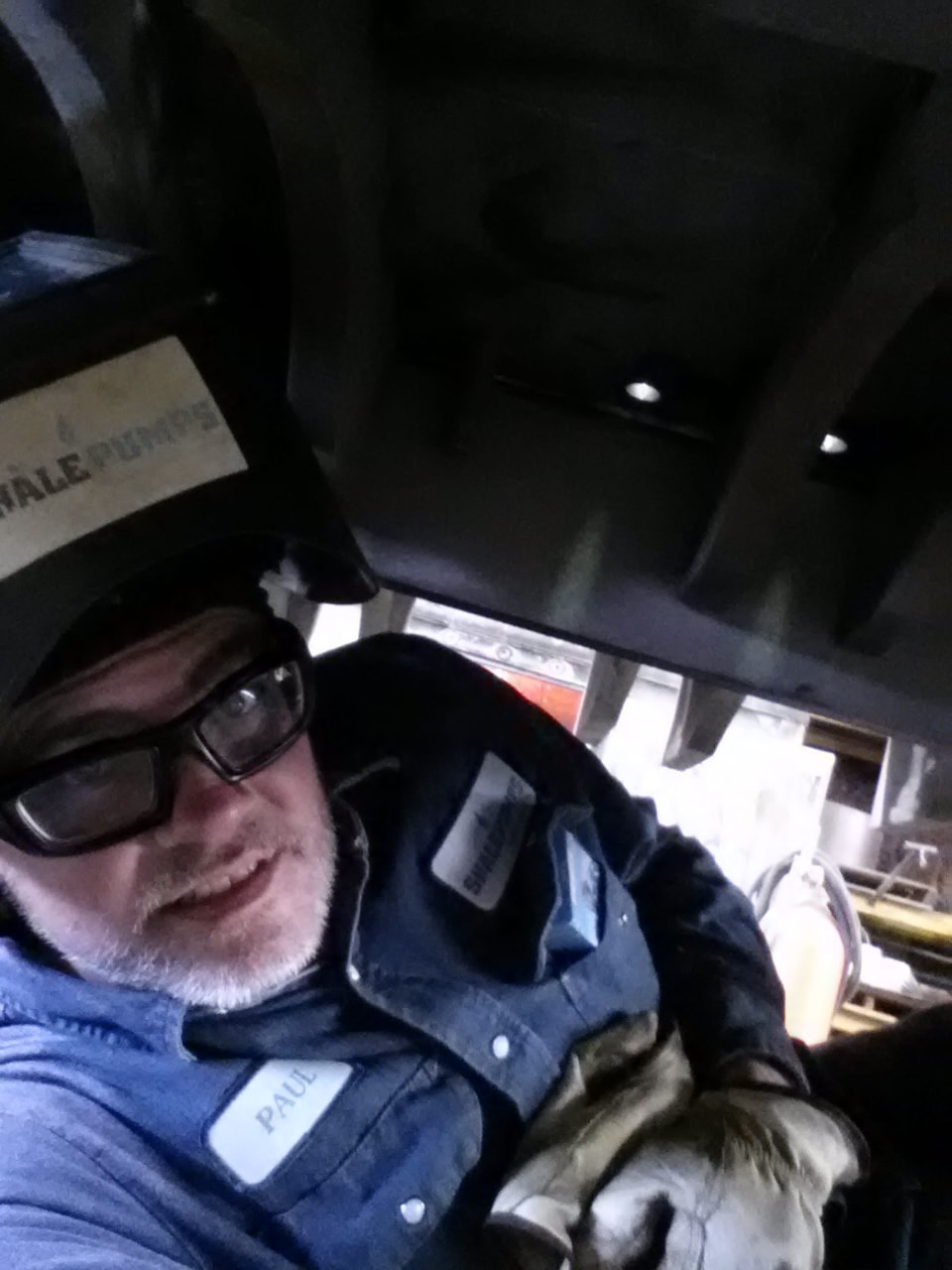 Selfie of welder from within the power frame of a mud pump